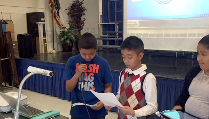 Three students learn public speaking skills while presenting for the class.