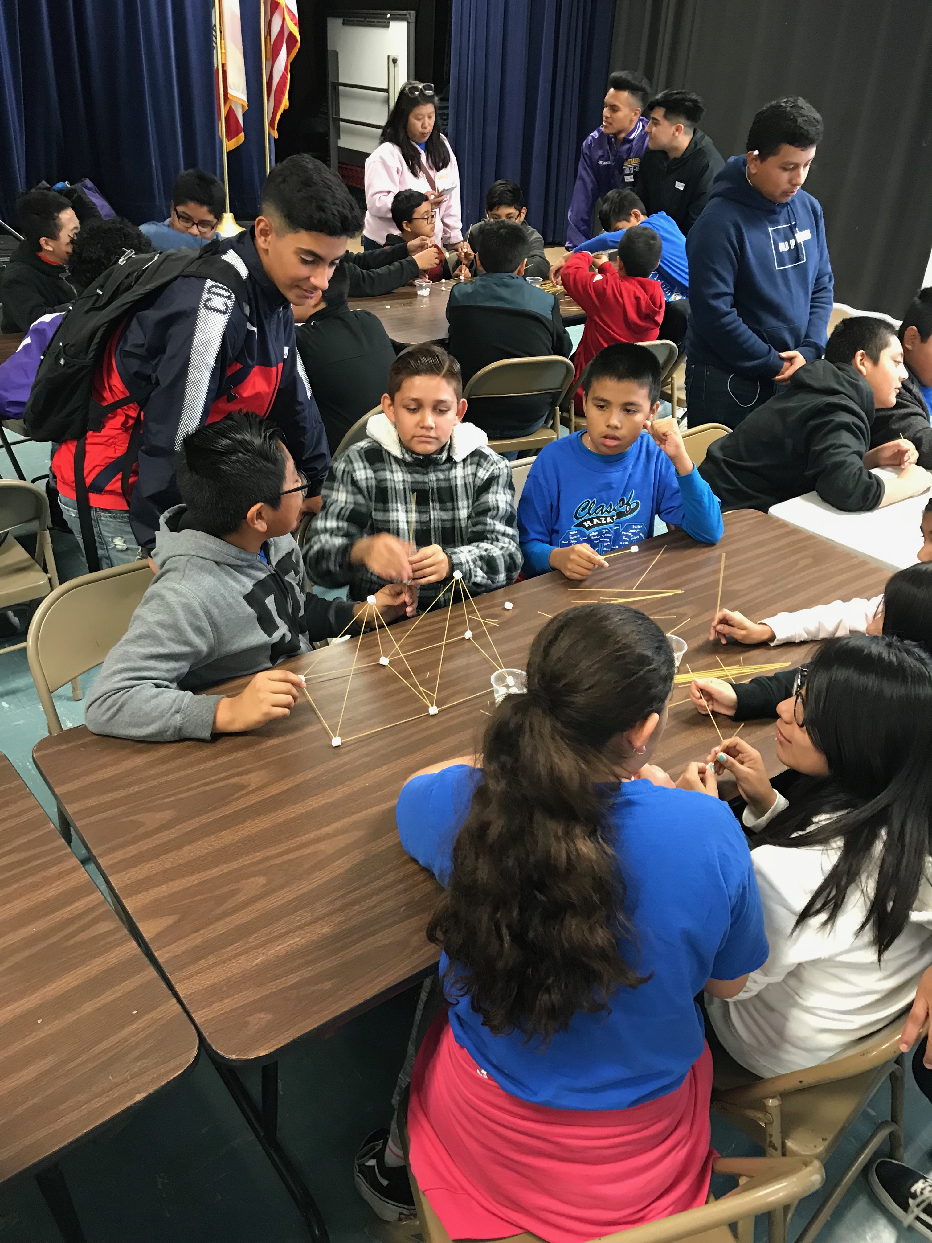 Students are analyzing the meaning behind the building blocks of towers in their group project.